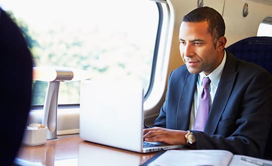 man in suit working on laptop in train